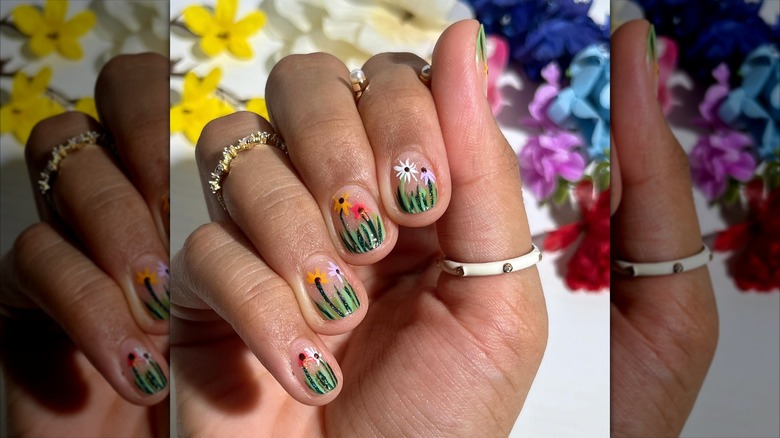 Curled hand showing nails with growing flowers and grass