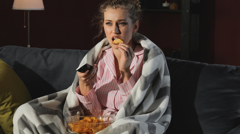Woman eating chips and watching tv late at night