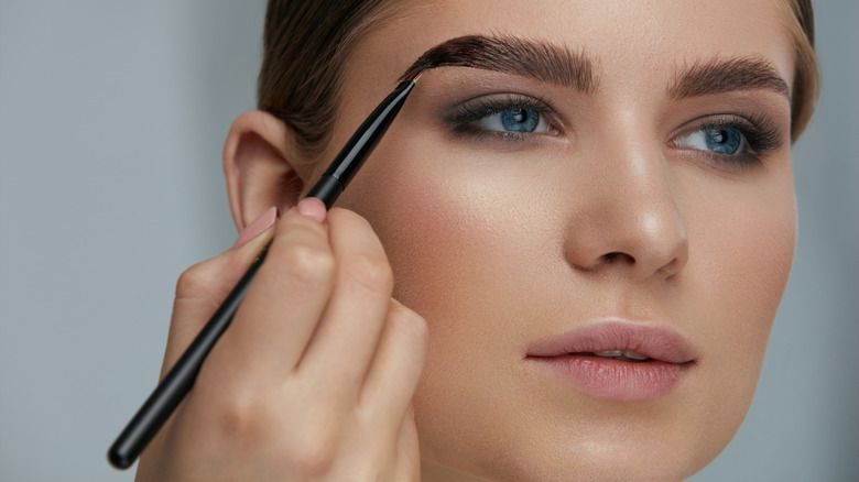 Woman using angled brush to fill in eyebrows