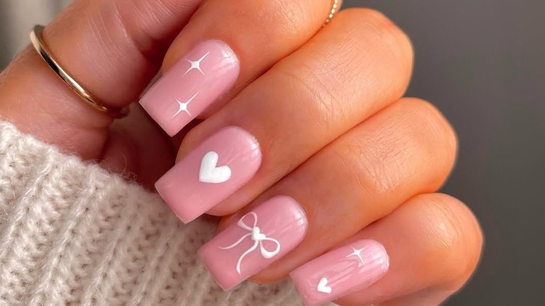 Light pink nails with pink hearts, pink bows and small pearls