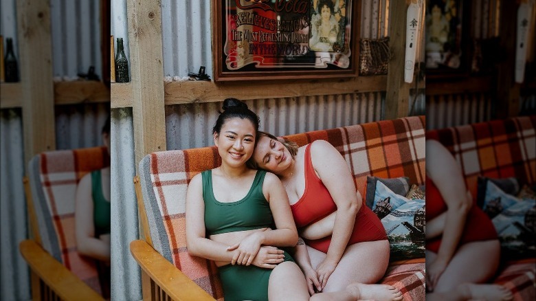 Two women sit on a couch while in swimsuits