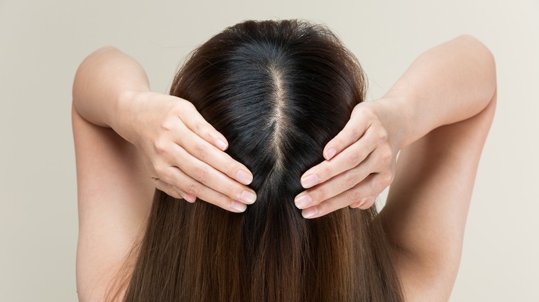 Woman parting hair to reveal scalp