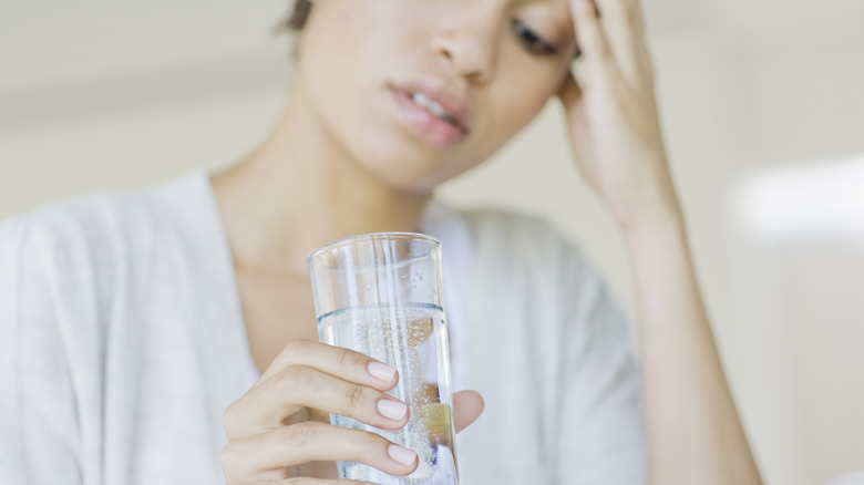 Woman with headache drinking water