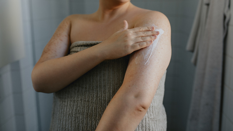 woman applying moisturizer to dry skin 