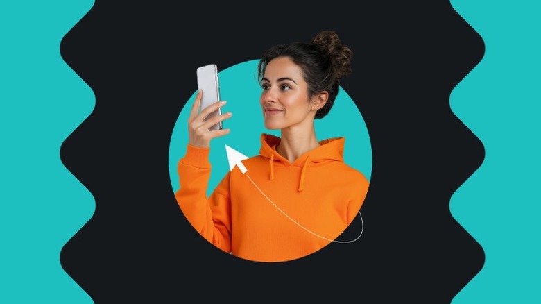 woman with orange hoodie holds phone up to face