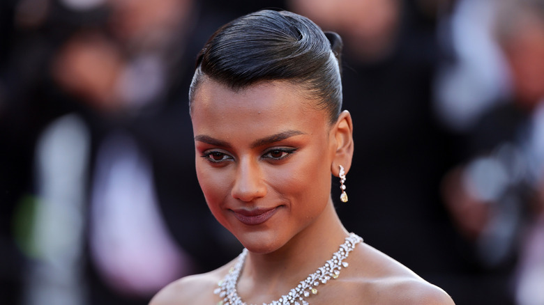 Simone Ashley smiling with an updo on the red carpet