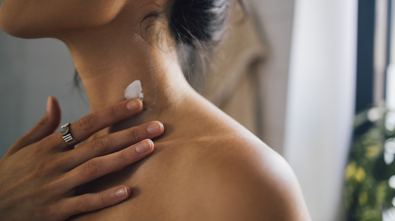 Woman moisturizing neck