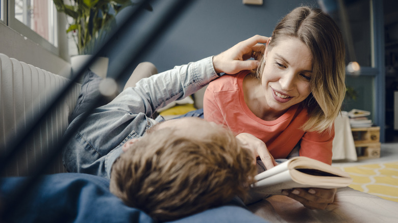 Man and woman laying on the floor, looking at each other with an open book