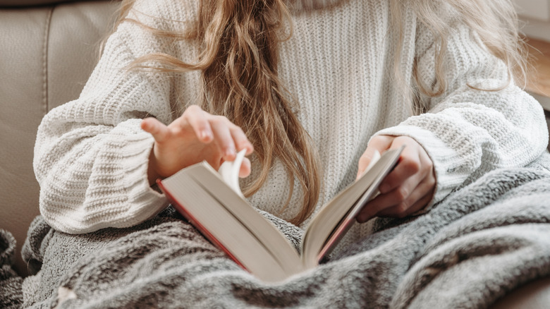 woman reading under a blanket