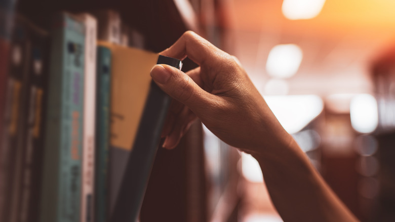 Close-up of a hand pulling a book from a shelf