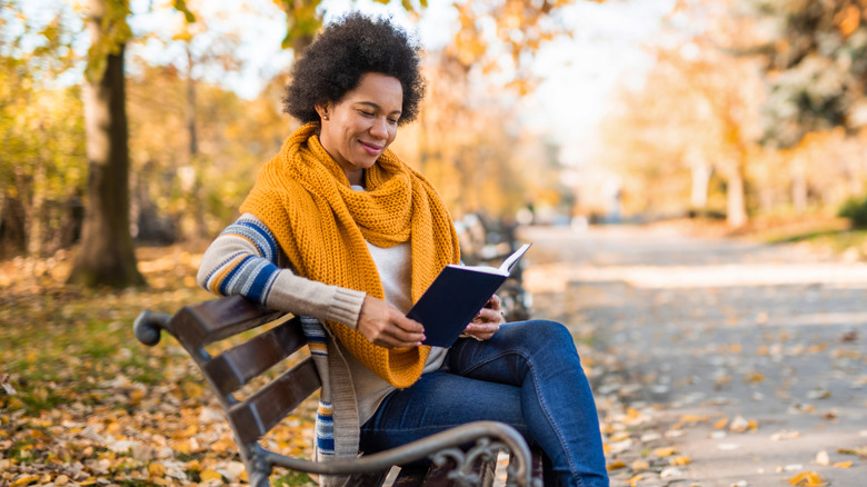 A woman reading outside on a bench