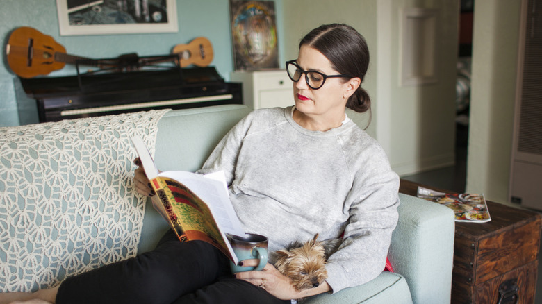 Woman sitting reading on the couch with her dog