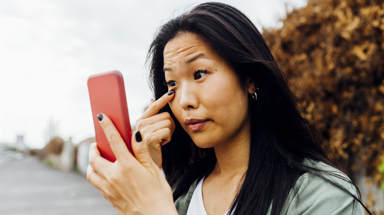 Woman inspecting her eyes in her phone camera