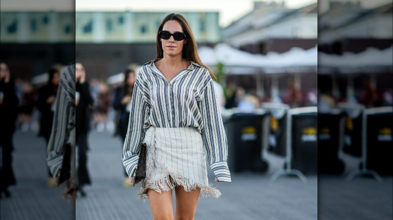 Woman in a button-down pinstripe shirt and skirt walking