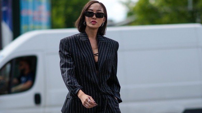 Chriselle Lim walks toward the camera in a pinstripe suit