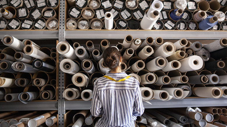 A woman looking at rolls of fabric