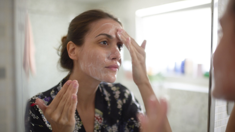 Woman washes face in mirror
