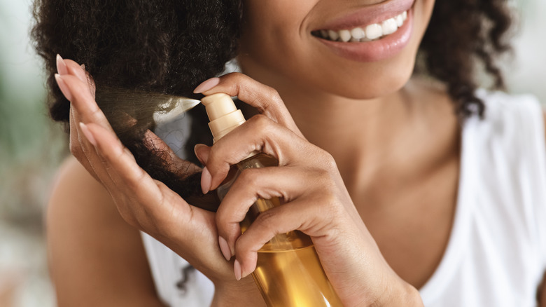 woman spraying almond oil in hair