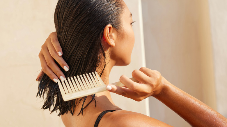 A woman with dark hair cutting her own hair