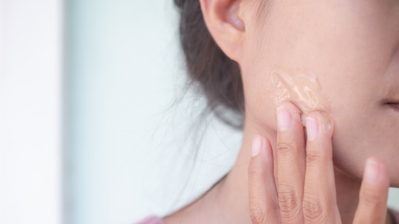 woman applying serum onto face