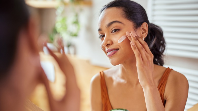 Woman moisturizing face