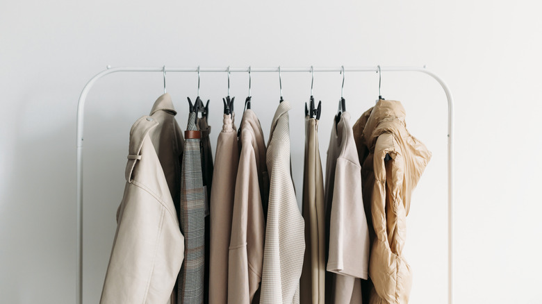 Neutral colored clothes hanging on a white rack