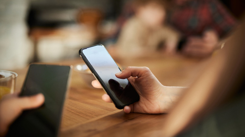 Hands holding phones at a table