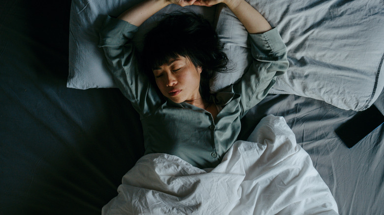 Woman sleeping in bed on her back