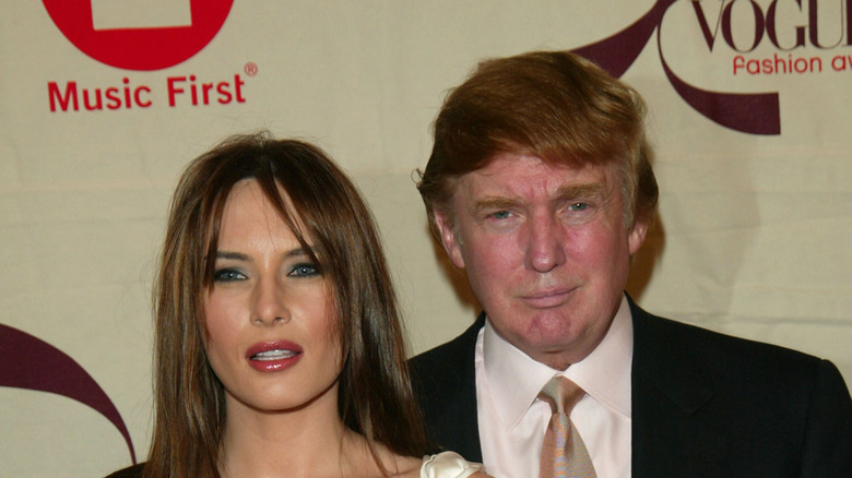 Melania Trump in a white dress and Donald Trump in a suit at an event