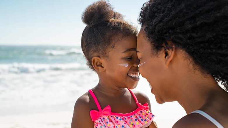 Woman and daughter smiling with sunscreen on