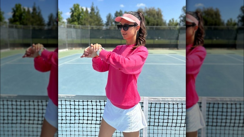 Eli Pironkova poses in a pink sweater on a tennis court