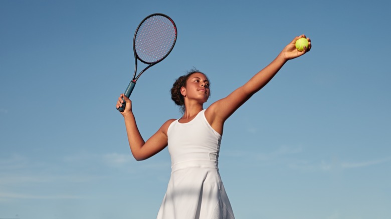 Woman poises to serve in a tennis dress