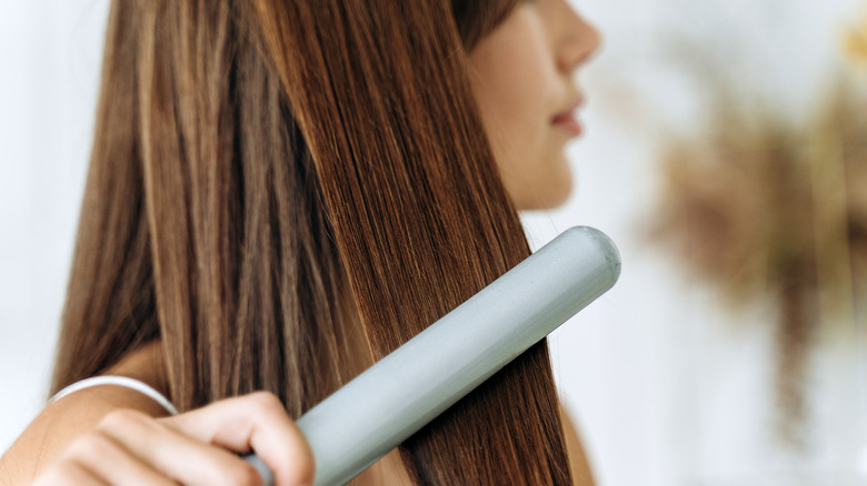 woman using straightener on hair