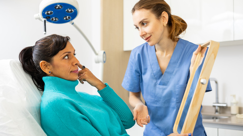 A woman in a green sweater having a consultation with a dermatologist