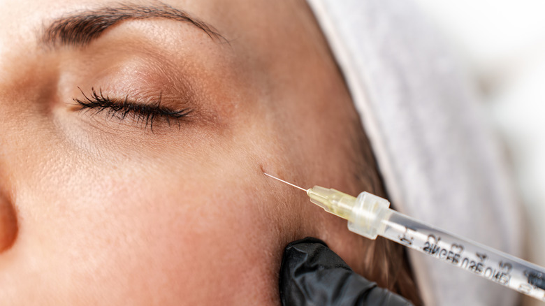 A close-up of a woman getting injections in her crows feet