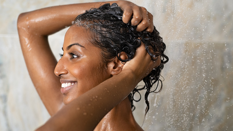 woman applying product to hair shower