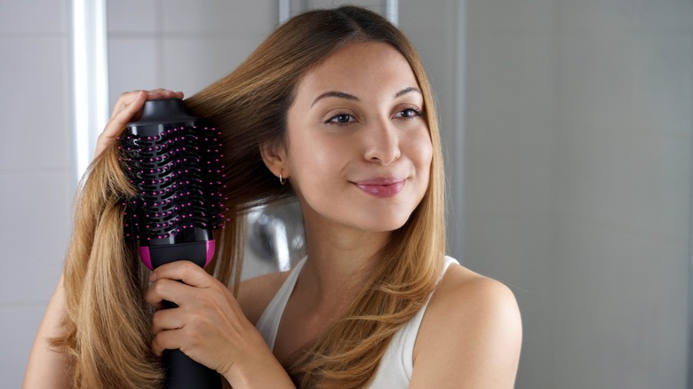 woman styles hair heat tool