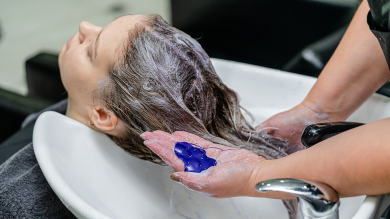 Hairstylist applying purple shampoo to client