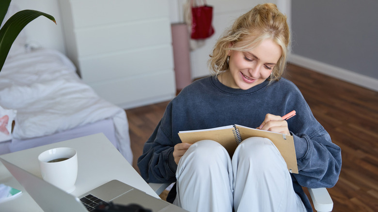 Woman writing in journal and smiling