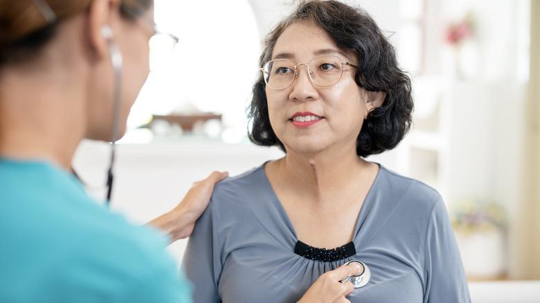 A healthcare worker holds a stethoscope to a patient's chest area