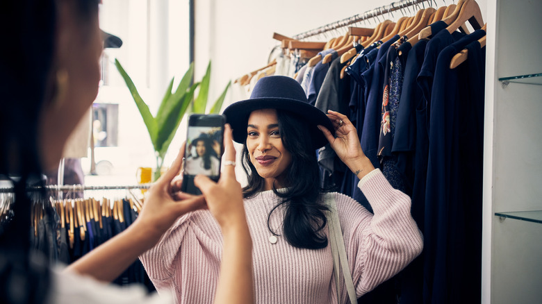 woman trying on a hat and getting photo taken