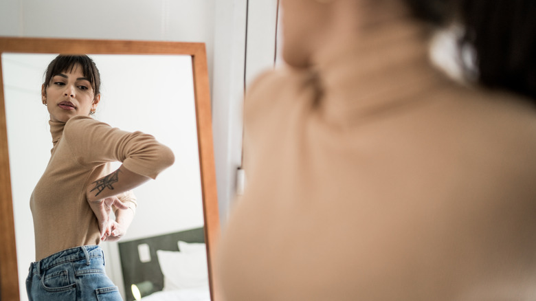 woman getting dressed in front of mirror