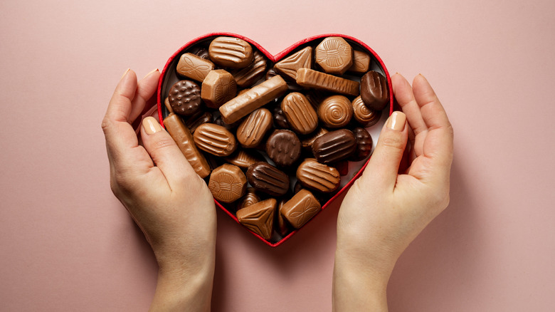 Hands holding a heart-shaped box of chocolates