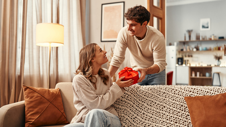 Flat lay shot of hands holding a package with heart wrapping paper and red ribbon