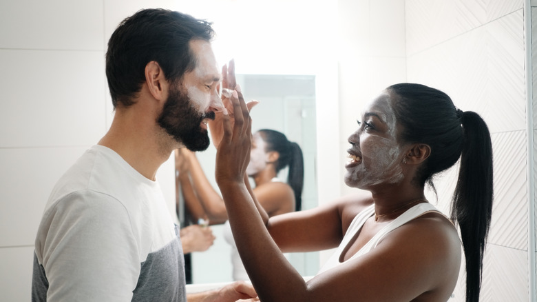 woman applies face mask to man