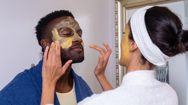 woman puts face mask on man