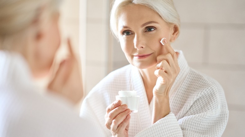 woman applying cream in mirror