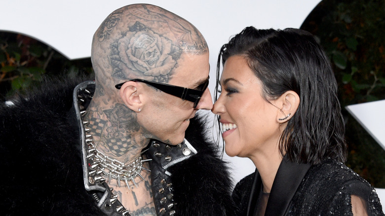 Koutney Kardashian and Travis Barker smiling face to face