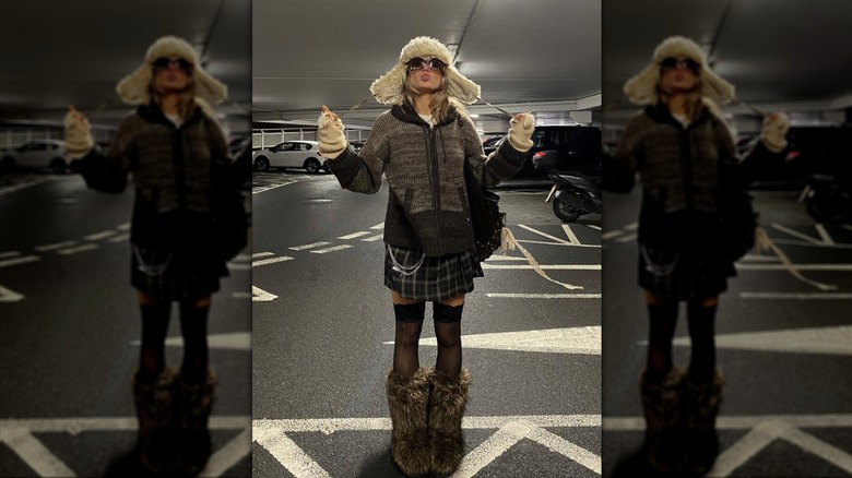 A woman wearing brown, fur boots, fur hat, and a mini skirt