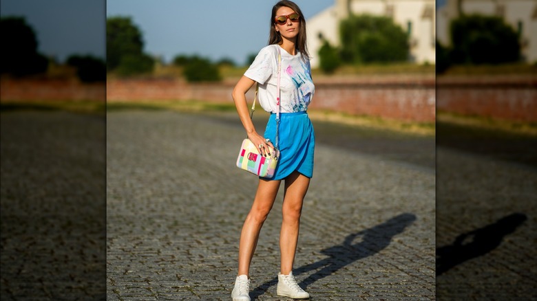 Young woman in a mini skirt and sneakers 